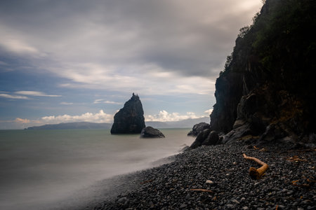 Breathtaking long-exposure shot of Ampere Beach in Quirino, Philippines, showcasing dramatic rock formations, a pebble beach, and the tranquil sea. The soft, blurred water creates a sense of peace and serenity, highlighting the natural beauty of this coastal landscape.の写真素材