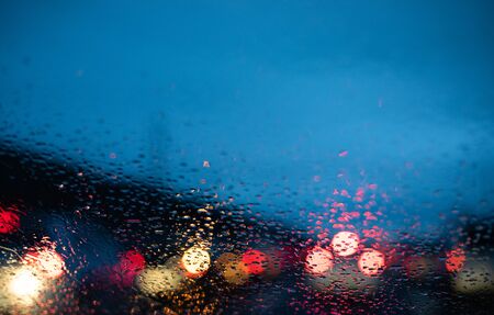 Blurred cars lights from inside a car with drops on the window