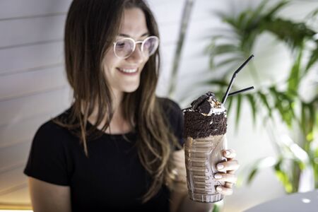 Beautiful women blurred holding a chocolate shake and cookies on a transparent glass with aboriginal...