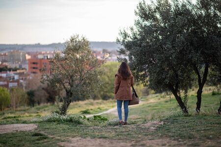 Beautiful woman standing on park during sunset back viewの写真素材