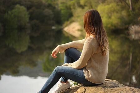 Woman sitting on a rock near the lake with copy spaceの写真素材
