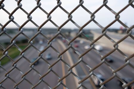 Blurred highway view through a metallic fence