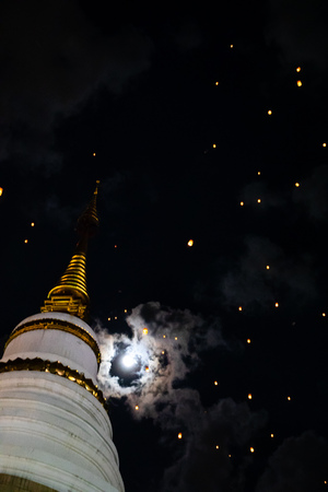 Loi Krathong and Yi Peng released paper lanterns on cloudy sky and moon and templeのeditorial素材