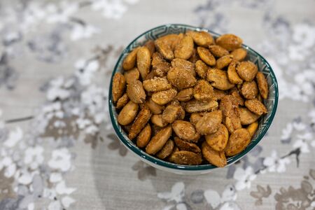 Toasted almonds on a bowl on a table with floral black and white decoration and copy space