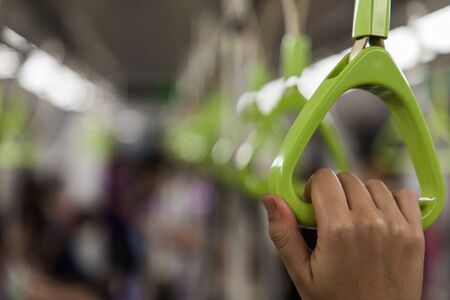 Close up of a woman hand grabbing a handle inside the metro of Singapore with copy spaceの写真素材