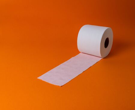 View of a white toilet paper roll over an orange background and copy spaceの写真素材