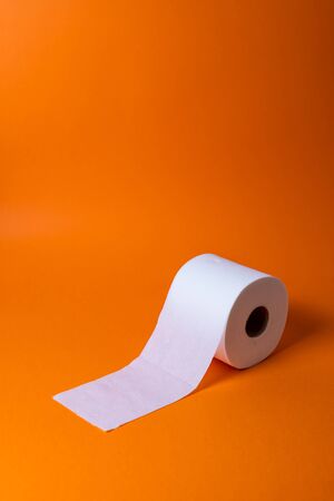 View of a white toilet paper roll over an orange background and copy spaceの写真素材