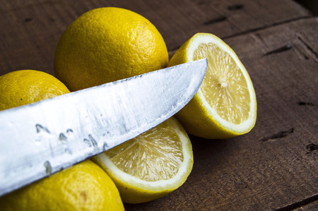 cut lemon with knife on wooden backgroundの写真素材