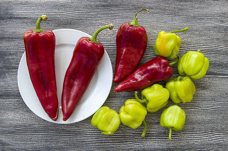 Pictures of red hot peppers and green stuffed peppers in the same plateの写真素材
