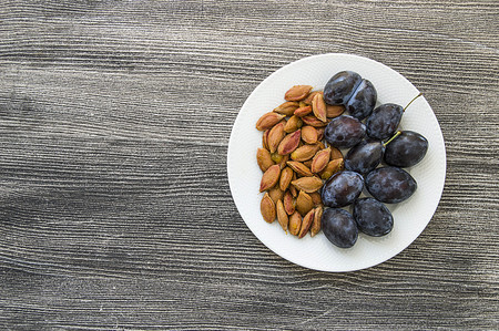Black natural plums and seeds in plates, Plums in white plates, Plum seedsの写真素材