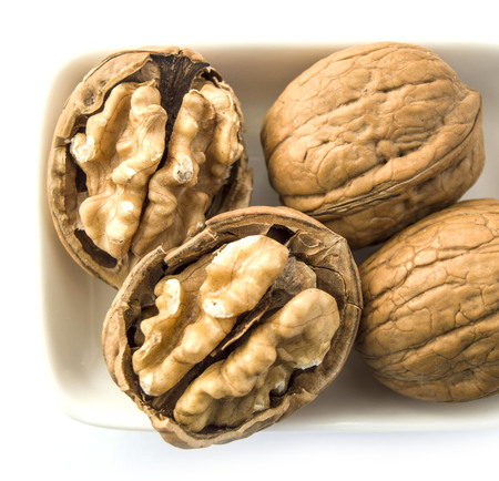 standing on the wooden plate on a white background dry walnut,