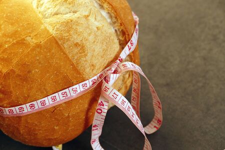 tape measure wrapped in a large bread, bread weighs weight, diet and bread,の写真素材