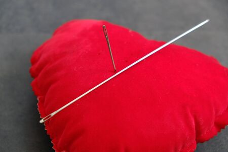 red pincushion and a large sewing needle, needle spell,の写真素材