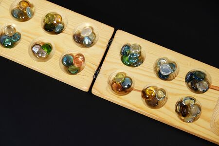 wooden mangala game, mangala game board and glass marbles, on black backgroundの写真素材