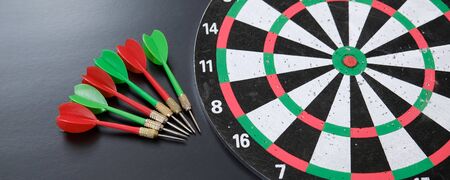 red, yellow, green dart arrows and dartboard, on black background