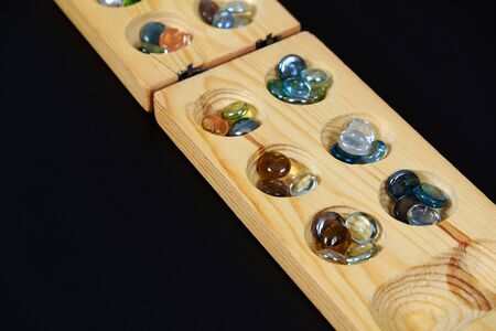 wooden mangala game, mangala game board and glass marbles, on black backgroundの写真素材