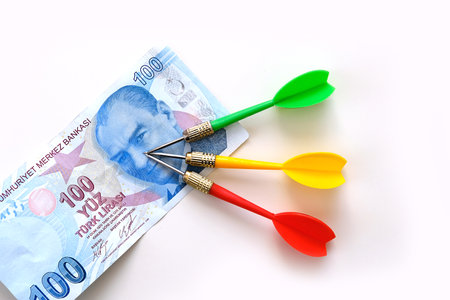 Investing with yellow, green and red darts and 100 Turkish lira on a white background, and Turkish...