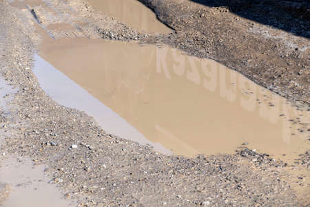 mud and dirty water puddle formed on the road after rain