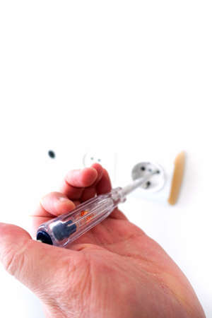 an electrician measuring the electricity in the socket with an electric control pen,
