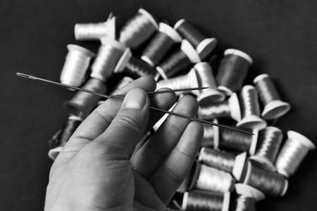 classic sewing needle and threads in a tailor's hand,sewing needle close-up,