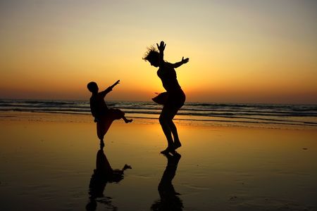 silhouette of mother and her son on the beach during sunsetの写真素材