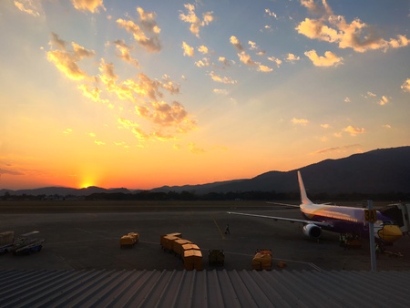Airplane at airport waiting for loading carton with dramatic sky backgroundの素材