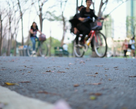 At the outdoor park, Asian family and couples are riding bicycles to relax in the evening, blurryの素材