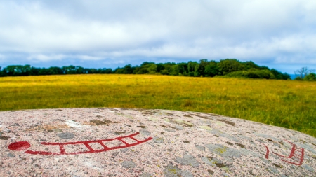 Colored stone carving of a ship with the surrounding environment  Rock carvings called petroglyphs depicting old ritual patterns of ships and stars and were created from the bronze age to the iron ageの写真素材