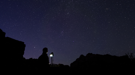 Astrophotographer standing behind his camera insside an old medieval ruinの写真素材