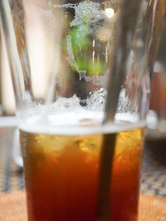 Cold beverage in a glass with ice and straws on the tableの写真素材