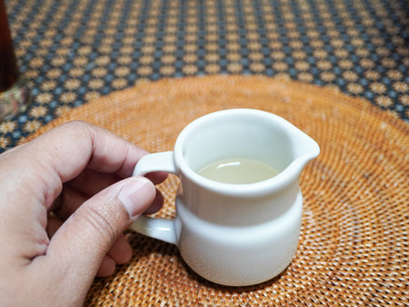 Hand holding a cup of tea on a tablecloth.の写真素材