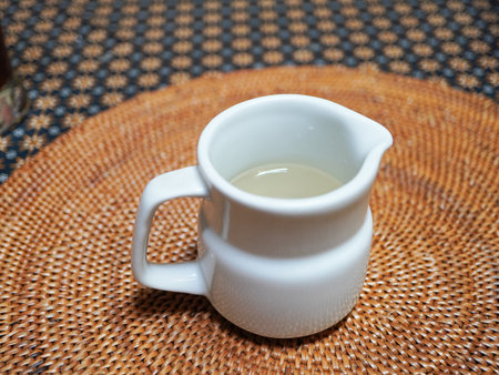 Milk in a white glass jug on a wicker tableclothの写真素材