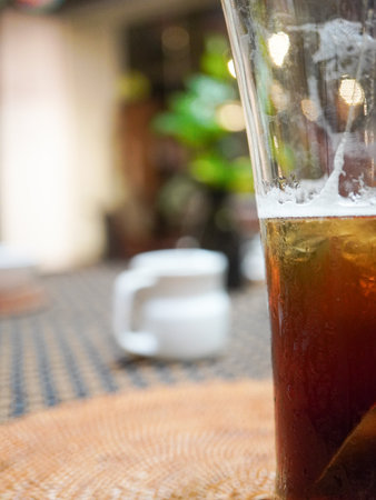 Glass of black tea with ice on table in coffee shop, stock photoの写真素材