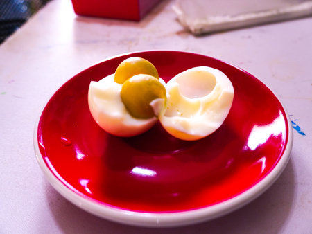 Boiled egg with olives in a red plate on a tableの写真素材