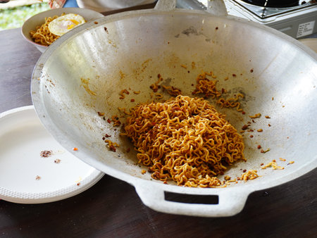 Fried instant noodle in a frying pan on wooden table.の写真素材