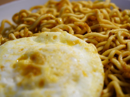 Fried instant noodle with fried egg on white plate close upの写真素材