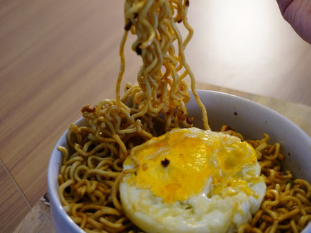 Instant noodles with fried egg in a bowl on the wooden table.の写真素材