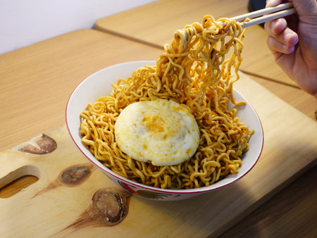 Noodles with egg in a bowl on a wooden table.の写真素材