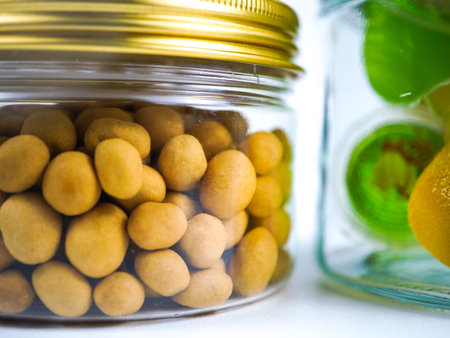 Glass jar with marinated macadamia nuts on white background.の写真素材