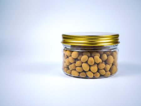 Yellow snack food in a glass jar on a white background, isolateの写真素材