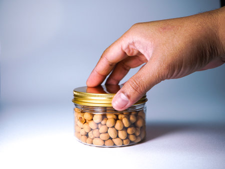 Hand holding a jar of chickpeas in a white background.の写真素材