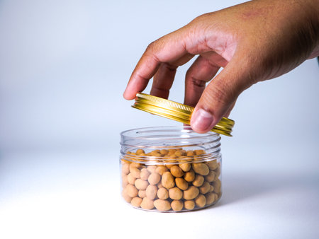 Close up of hand holding a jar full of beans on white backgroundの写真素材