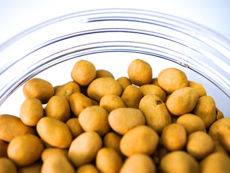 Pile of small yellow peanuts in a glass jar on white backgroundの写真素材