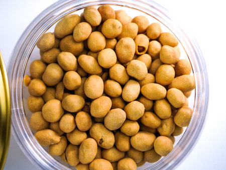 Sugar coated peanuts in a glass bowl on a white background.