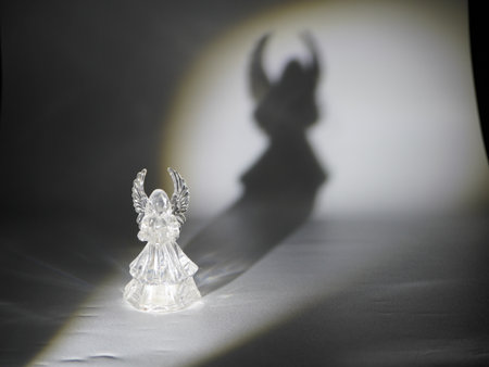 Angel figurine in the shadow on a white backgroundの写真素材