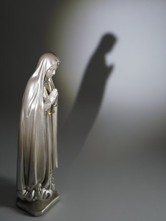Statue of the Virgin Mary with a shadow on a white backgroundの写真素材