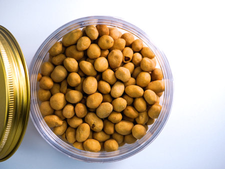 Sugar coated peanuts in a glass jar on a white background.の写真素材
