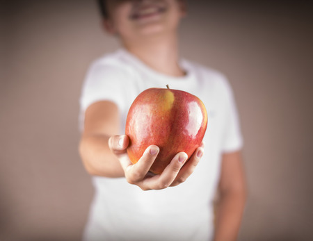 people, healthy food, children and happiness concept. child gives an apple smiling.の写真素材