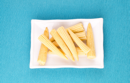 mini corn, canned lies on a rectangular white plateの写真素材