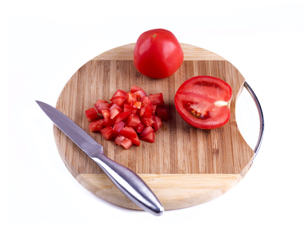 Tomato sliced on a circular wooden board on a white background. Tomato cubes, a knife, a wooden board, white background. Three types of slicing tomatoes isolated.の写真素材
